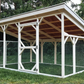 Wooden chicken coop with a roof in a grassy area with trees in the background