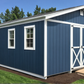 Blue storage shed with white trim in a backyard setting
