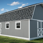 Gray storage building with white trim on a grassy area with trees and a fence in the background.