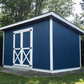 Blue storage shed with white trim in a garden setting